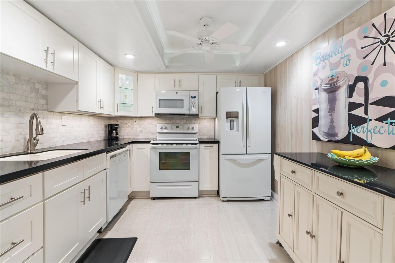 Large Kitchen with luxury vinyl tile, stone countertops, white appliances, rolling pantry cart, and ceiling fan