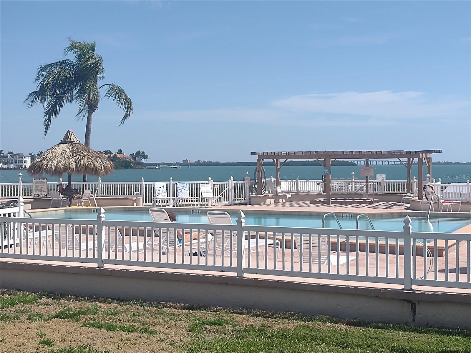 Large heated pool with spacious deck area. Pergola covered area is the spa. The bridge at the north end of the Skyway Bridge is in the background.