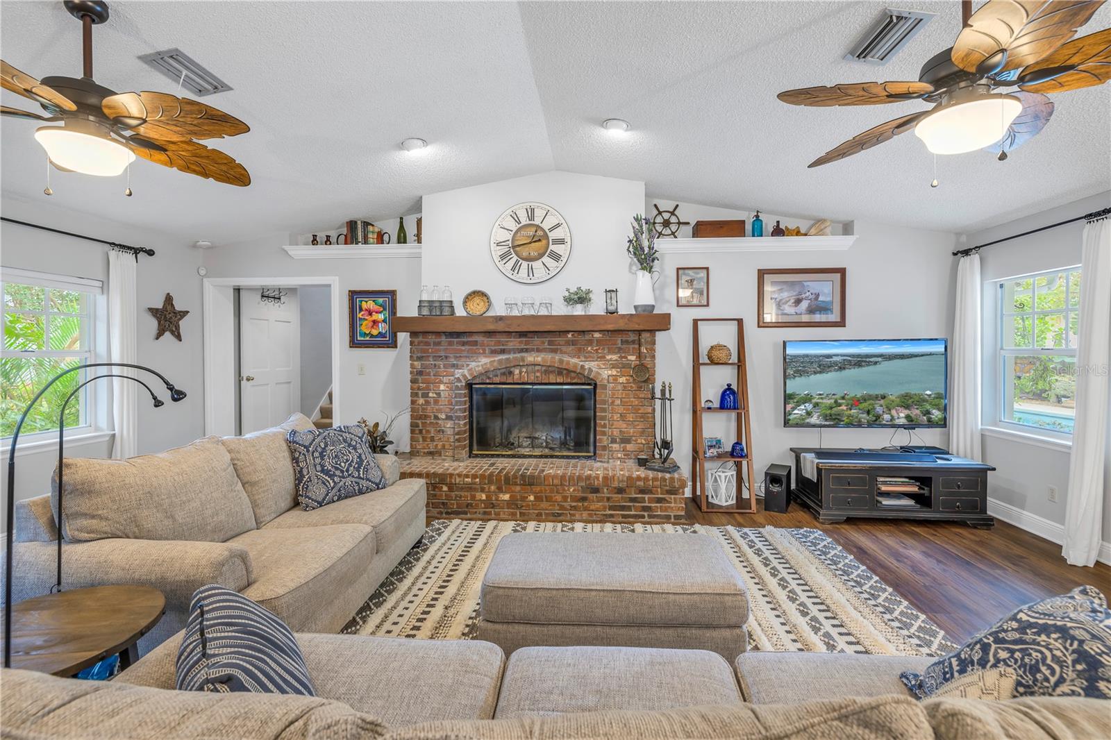 Family room with working wood burning fireplace, vaulted ceilings. You can see the waterfront and the pool from this large gathering space.