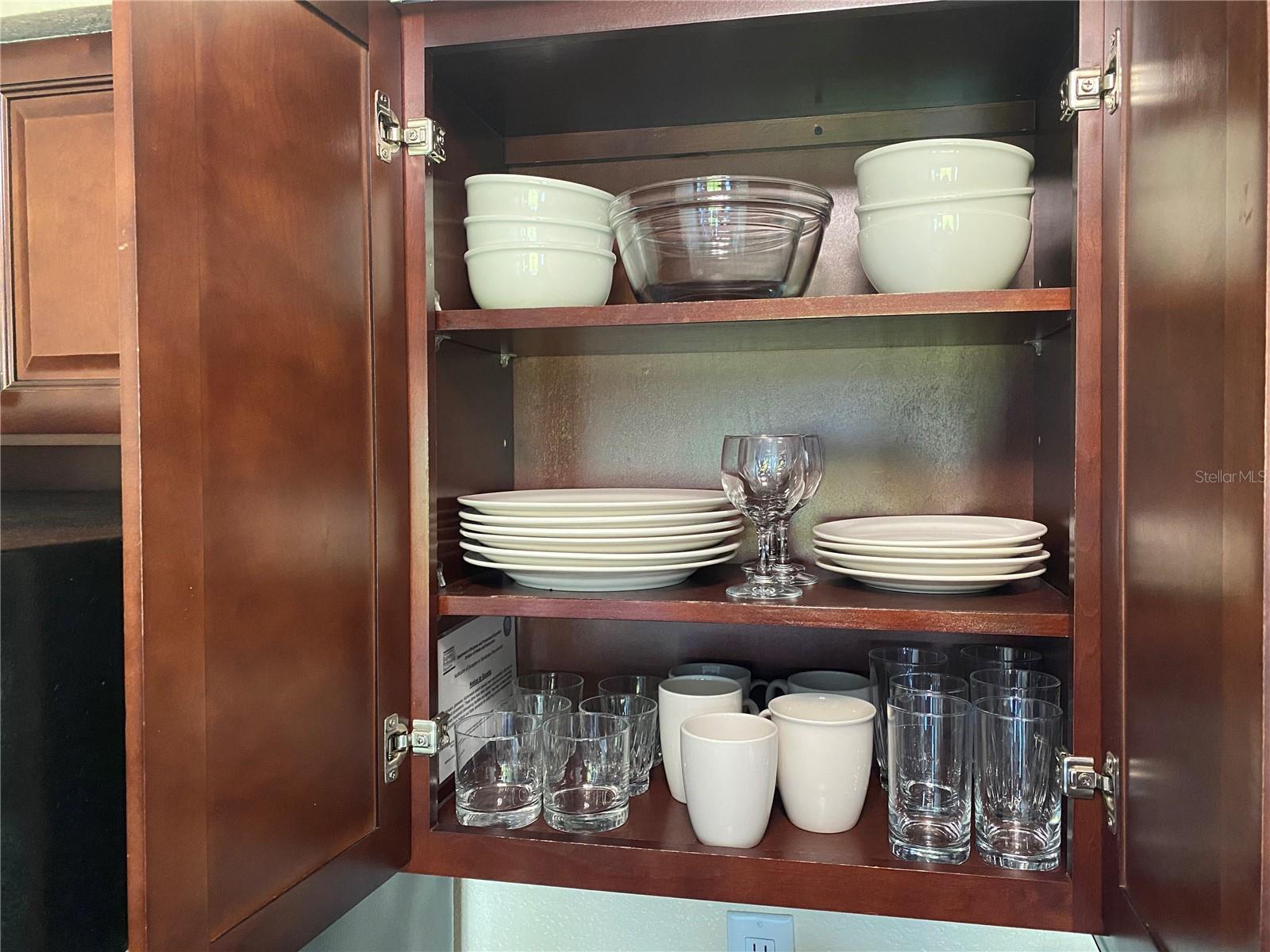 The kitchen is fully stocked with dishes and glassware