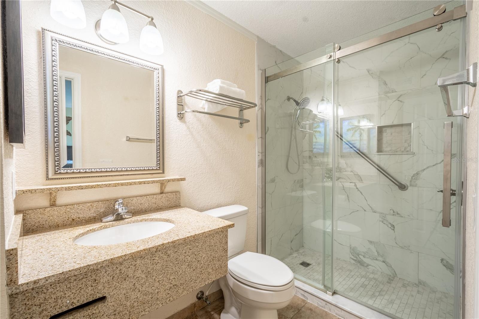 Primary bath includes mirrored sink with granite counter and a walk-in shower.