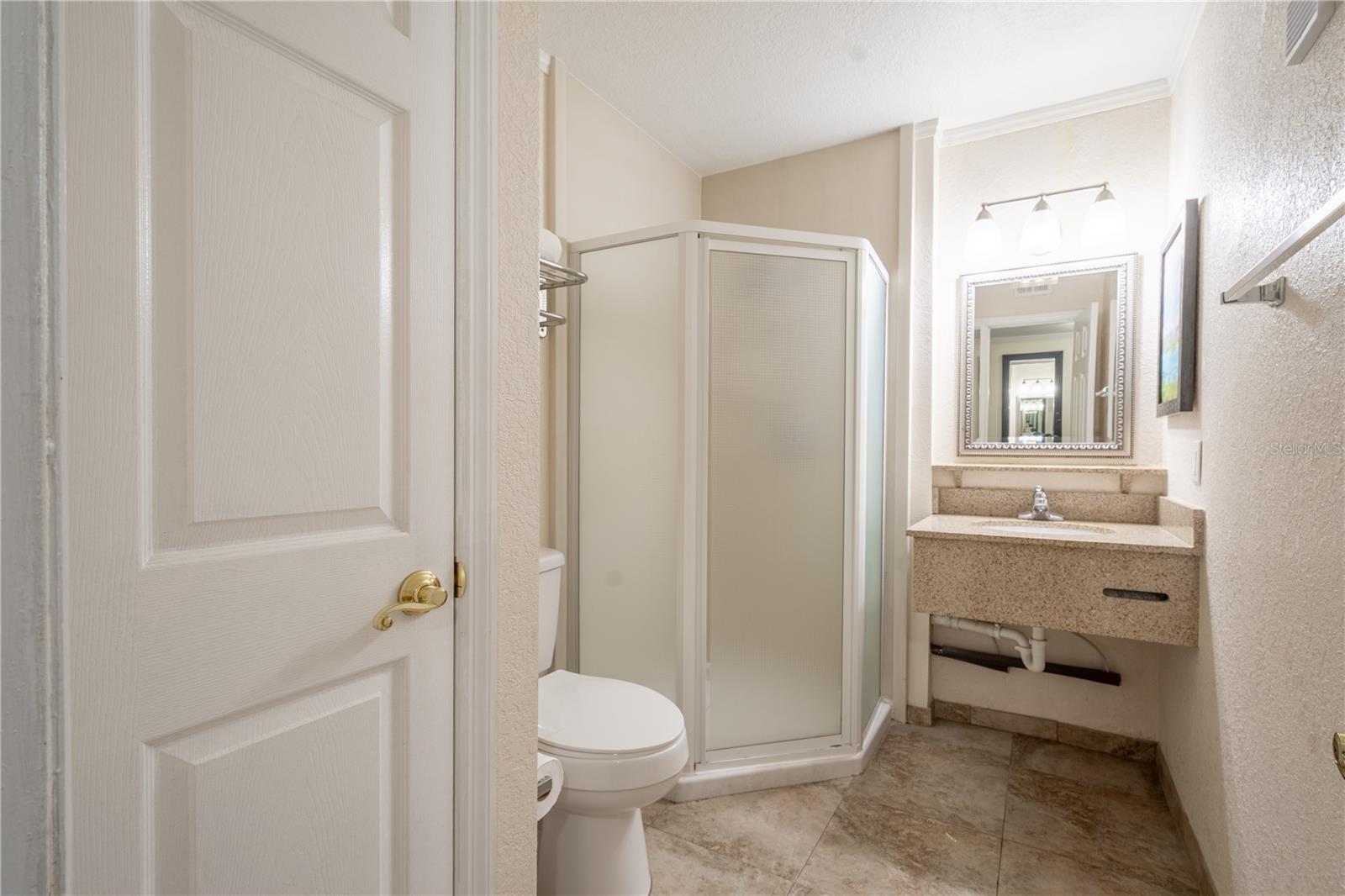 Bathroom 2 features a mirrored sink with granite counter, and a walk in shower