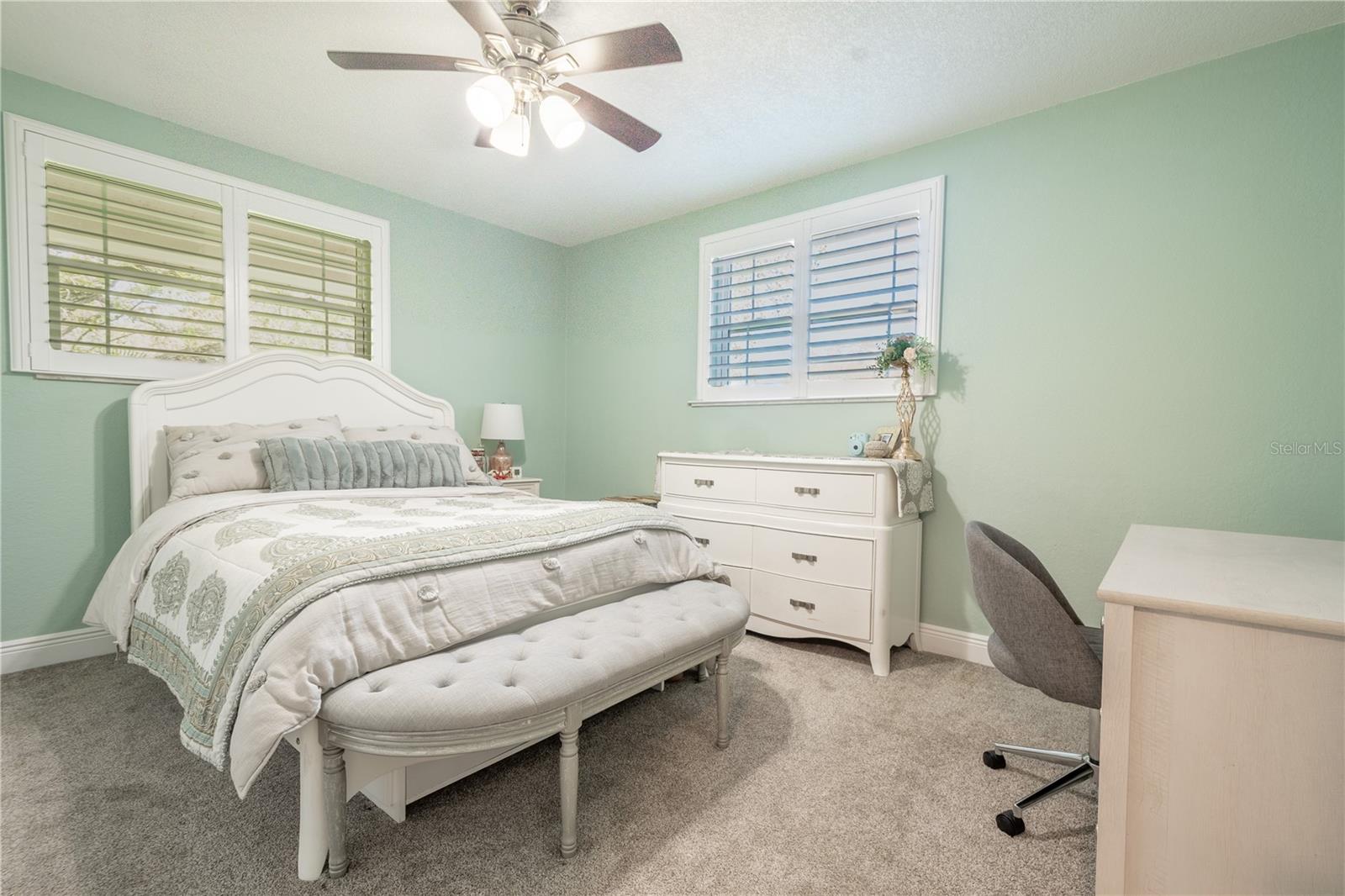 Bedroom 4 features neutral tones, plush carpet, plantation shutters, a ceiling fan and built-in closet.