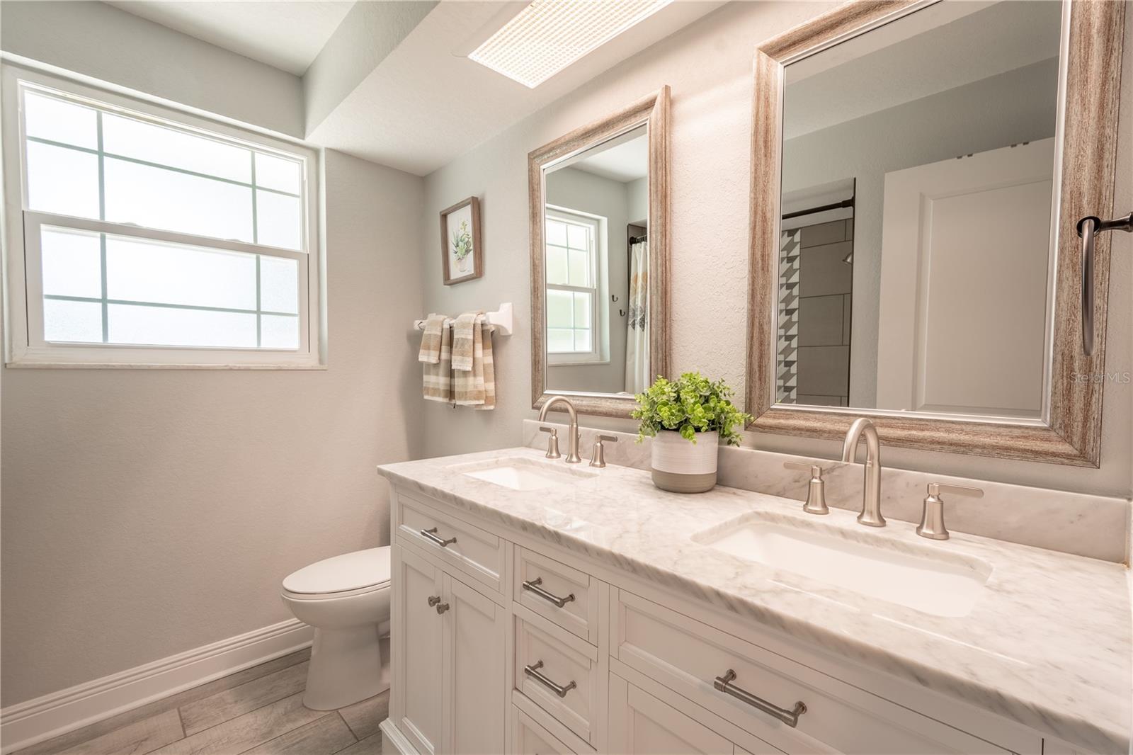The upstairs full bath features a dual sink mirrored vanity with stone counter top and ceramic tile flooring.
