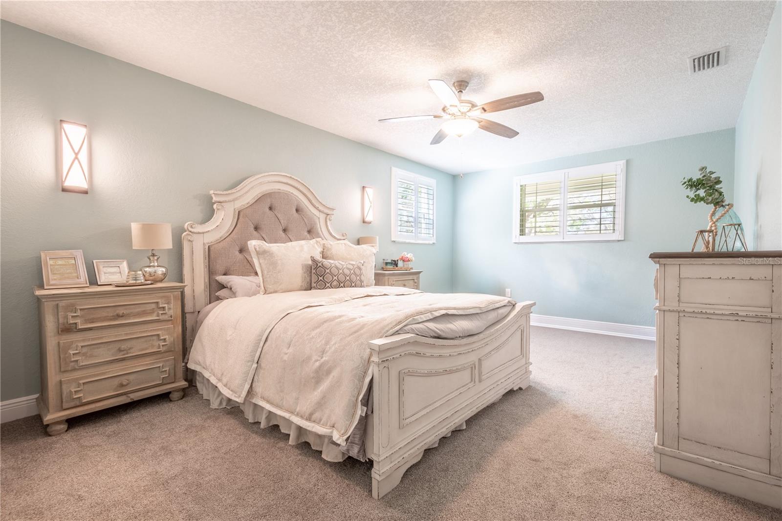 The upstairs primary bedroom features plantation shutters, plush carpeting and an ensuite bath.