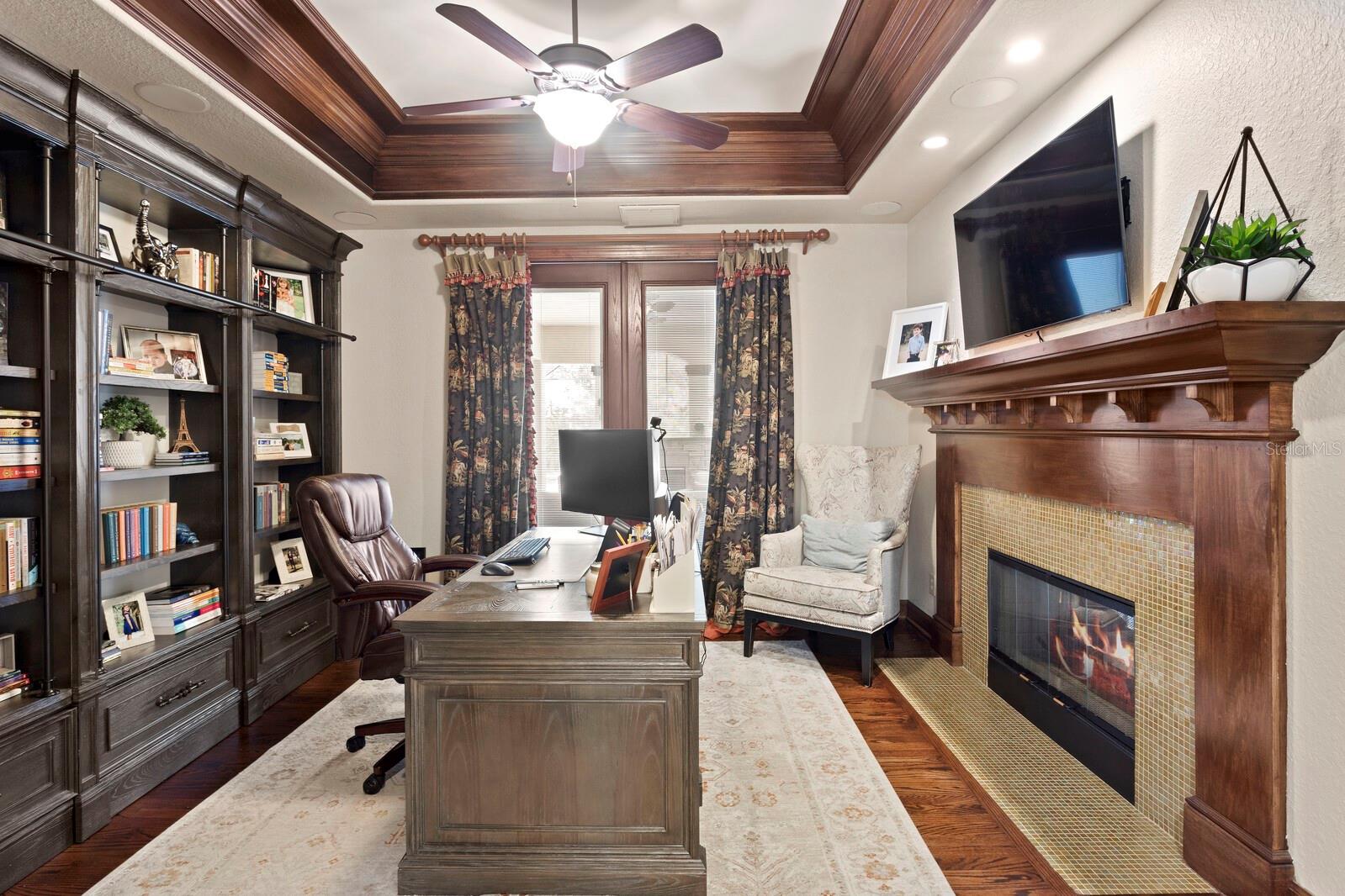 A gentleman's study with stained moulding & fireplace with French door access to the outdoor living space!