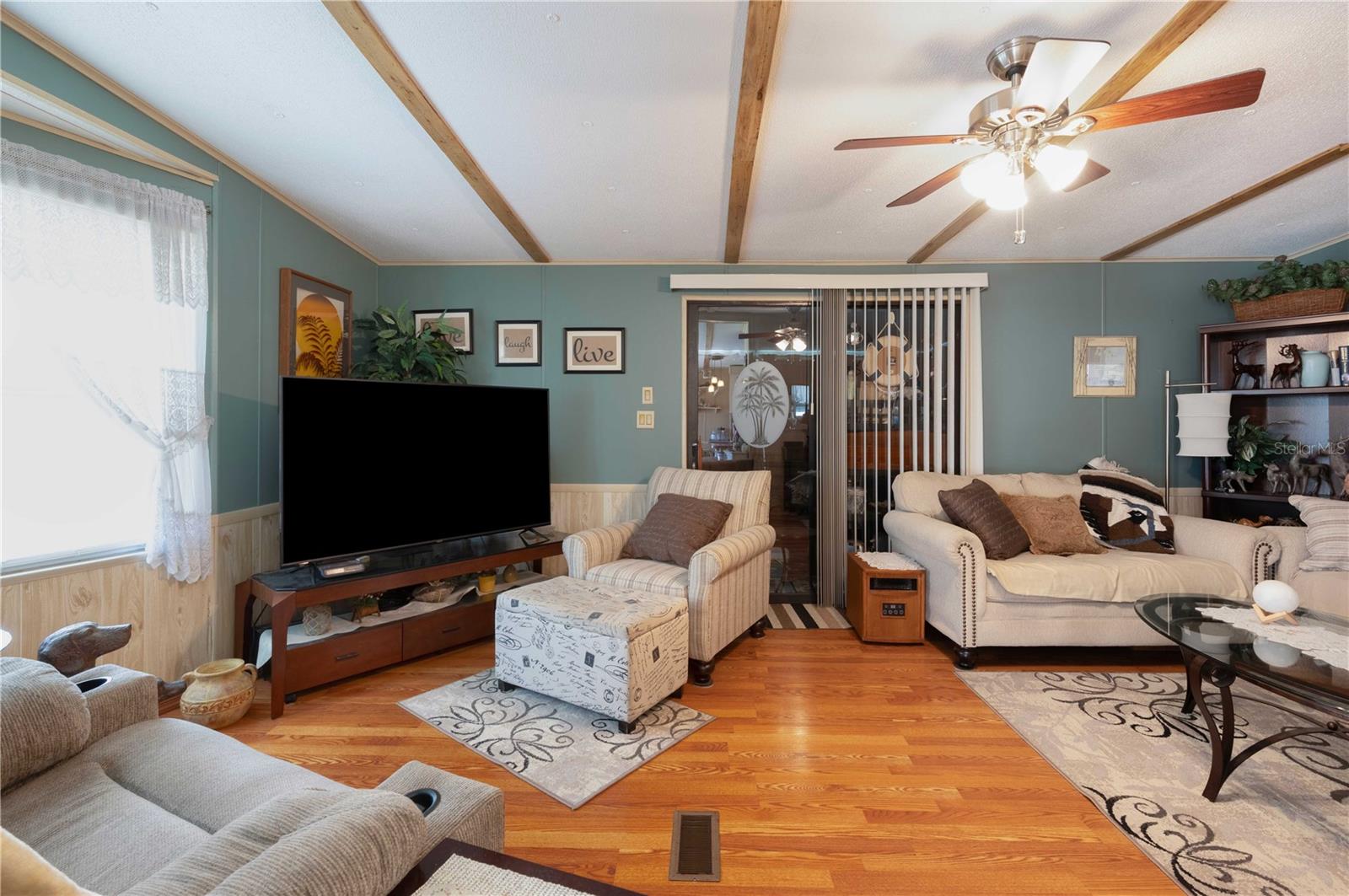 Living room has laminate flooring, ceiling fan, and nicely painted.