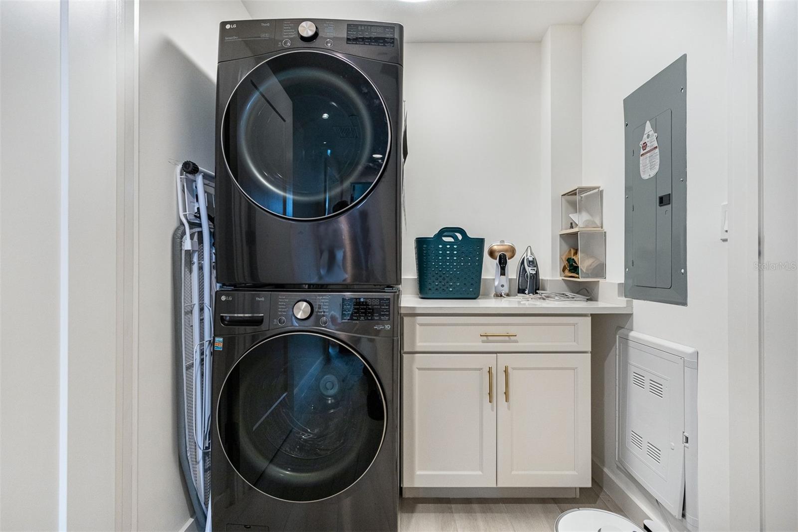 Desirable laundry room with stackable washer and dryer, plus folding area and cabinets