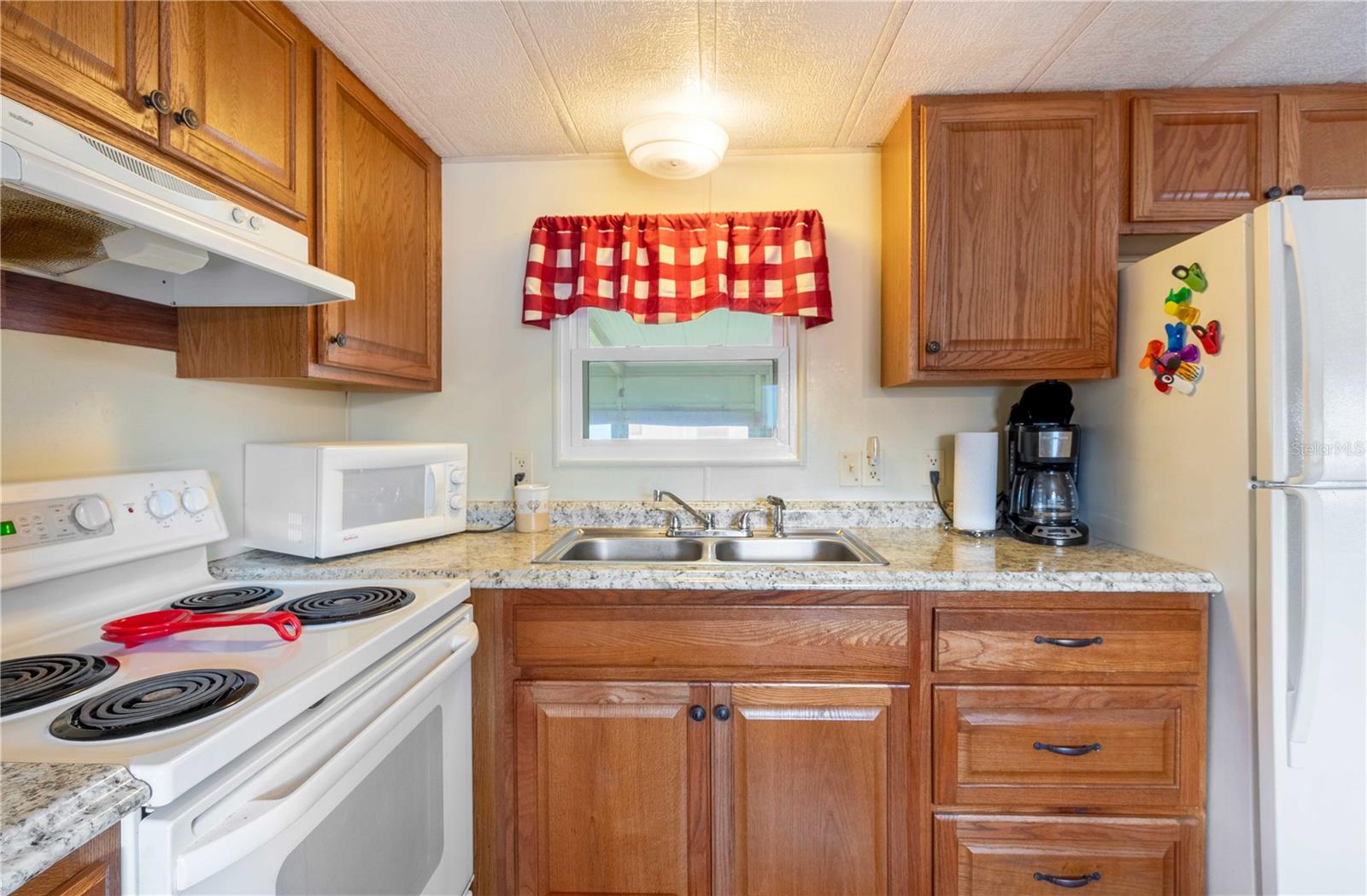 Kitchen has updated wood cabinets, range, microwave, and refrigerator.