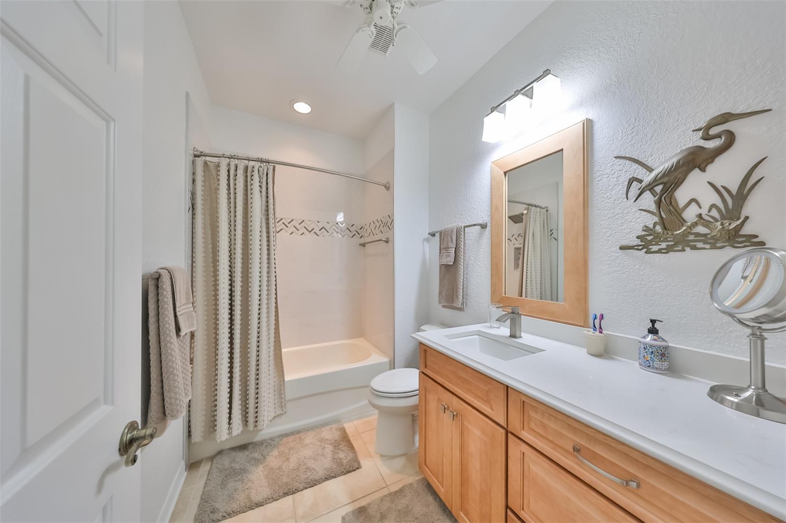 Updated guest bathroom with dual sinks, matching wood features and neutral colors.