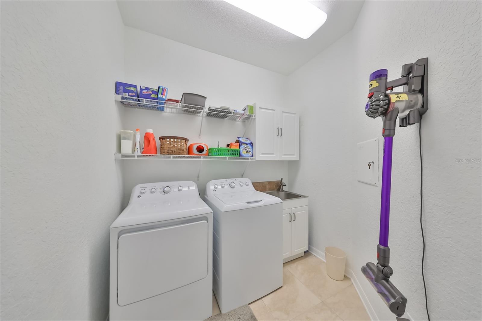 Laundry Room is conveniently upstairs with a utility sink, shelving and bright lights.