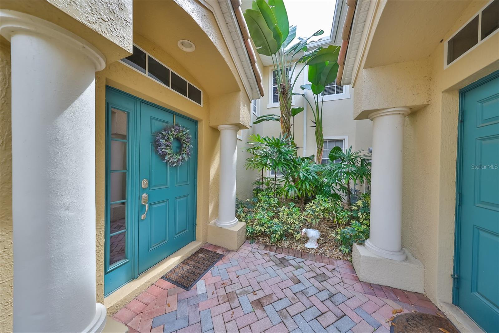 Front entrance of this luxury Tuscan-style condo unit is beautifully manicured and well maintained. Side lights and overhead windows allow Florida sunshine into the condo.