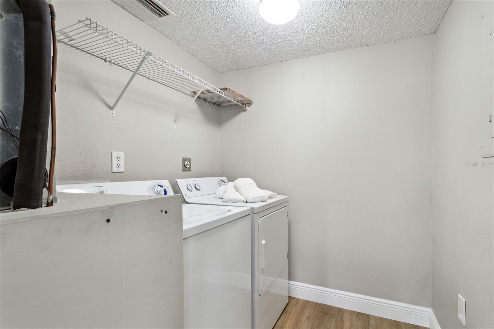Roomy and bright laundry room includes washer and dryer and shelving. Extra space for storage and easy reach for A/C filters and water heater in same room. Freshly painted and new flooring.