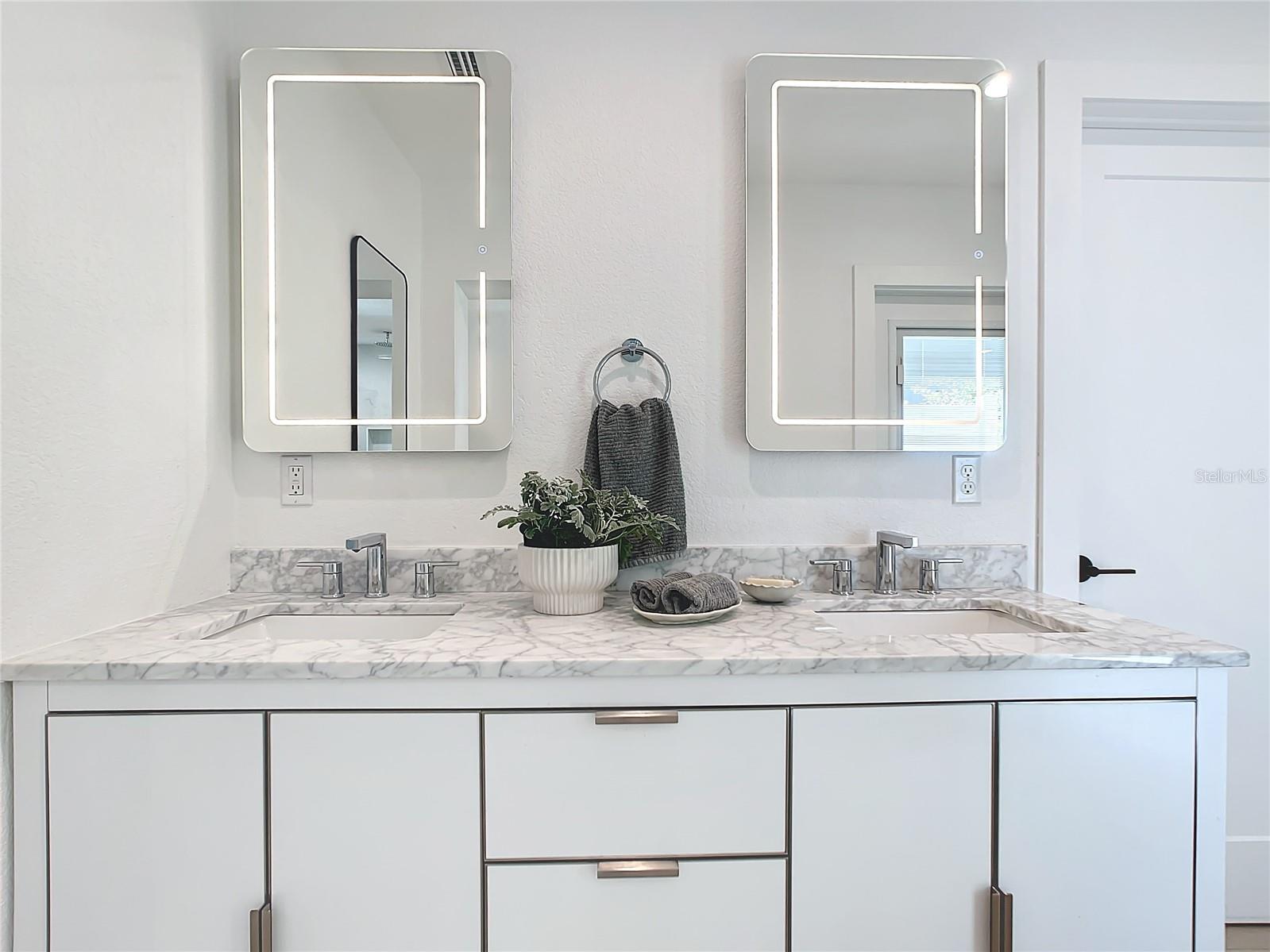 Modern vanity with solid surface countertops and illuminated mirrors