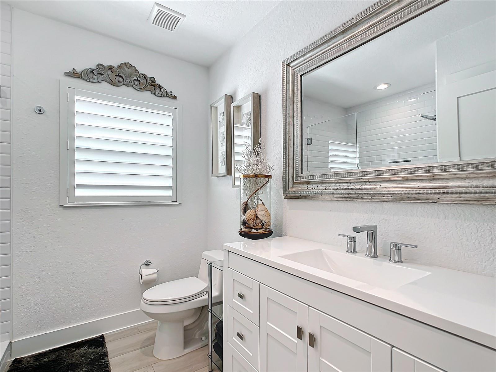 The 2nd bathroom, generous in size, boasts a bright white vanity with a solid surface countertop