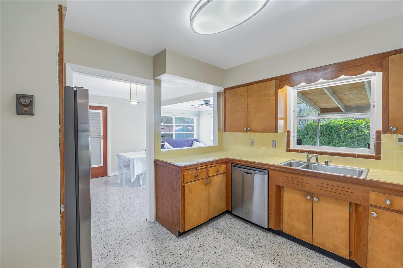 Note the pristine, original 2 tone tile countertops complimented with a newer stainless steel dishwasher.