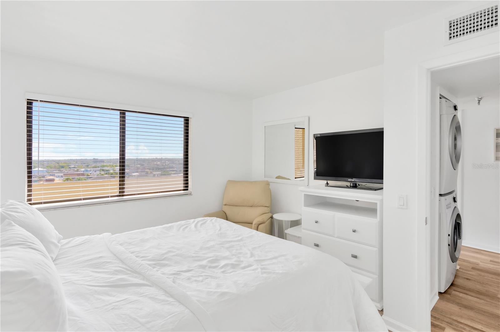Guest bedroom is crisp & inviting with large window for natural light.