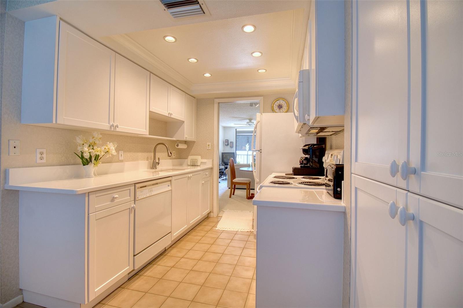 Bright white kitchen with recessed lighting in cove ceiling.