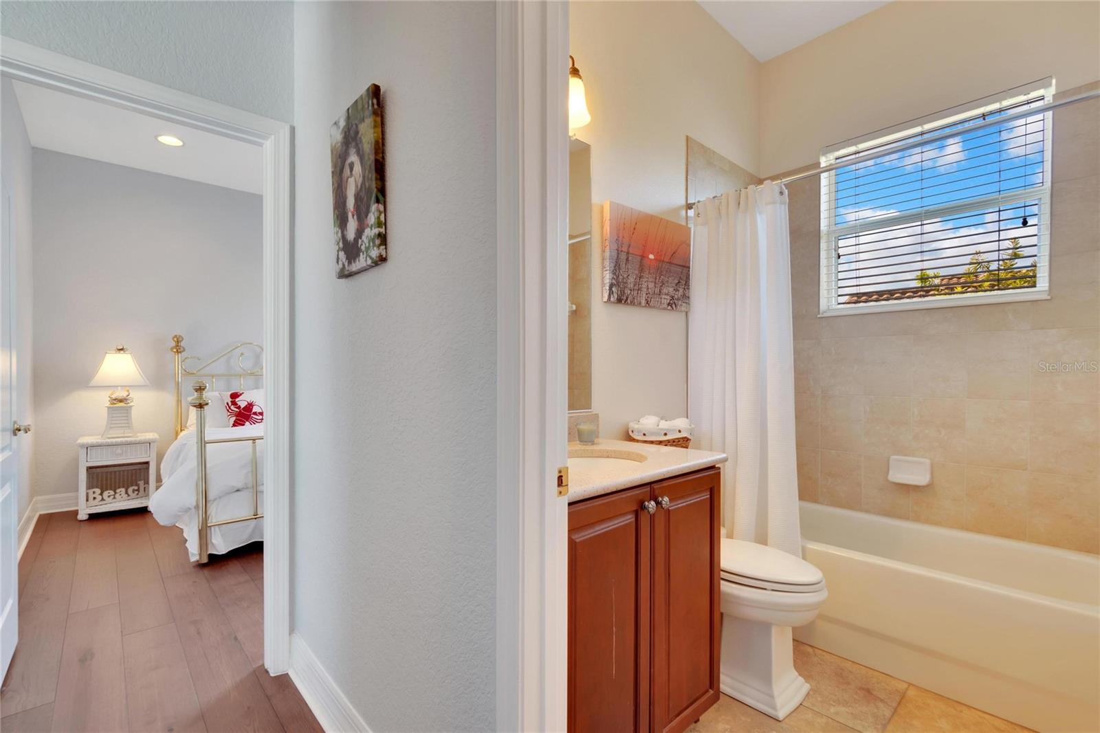Second full bath with window over shower tub combo, tile flooring and tall solid wood cabinet w/solid surface counter top. Note the extra thick floor molding throughout!