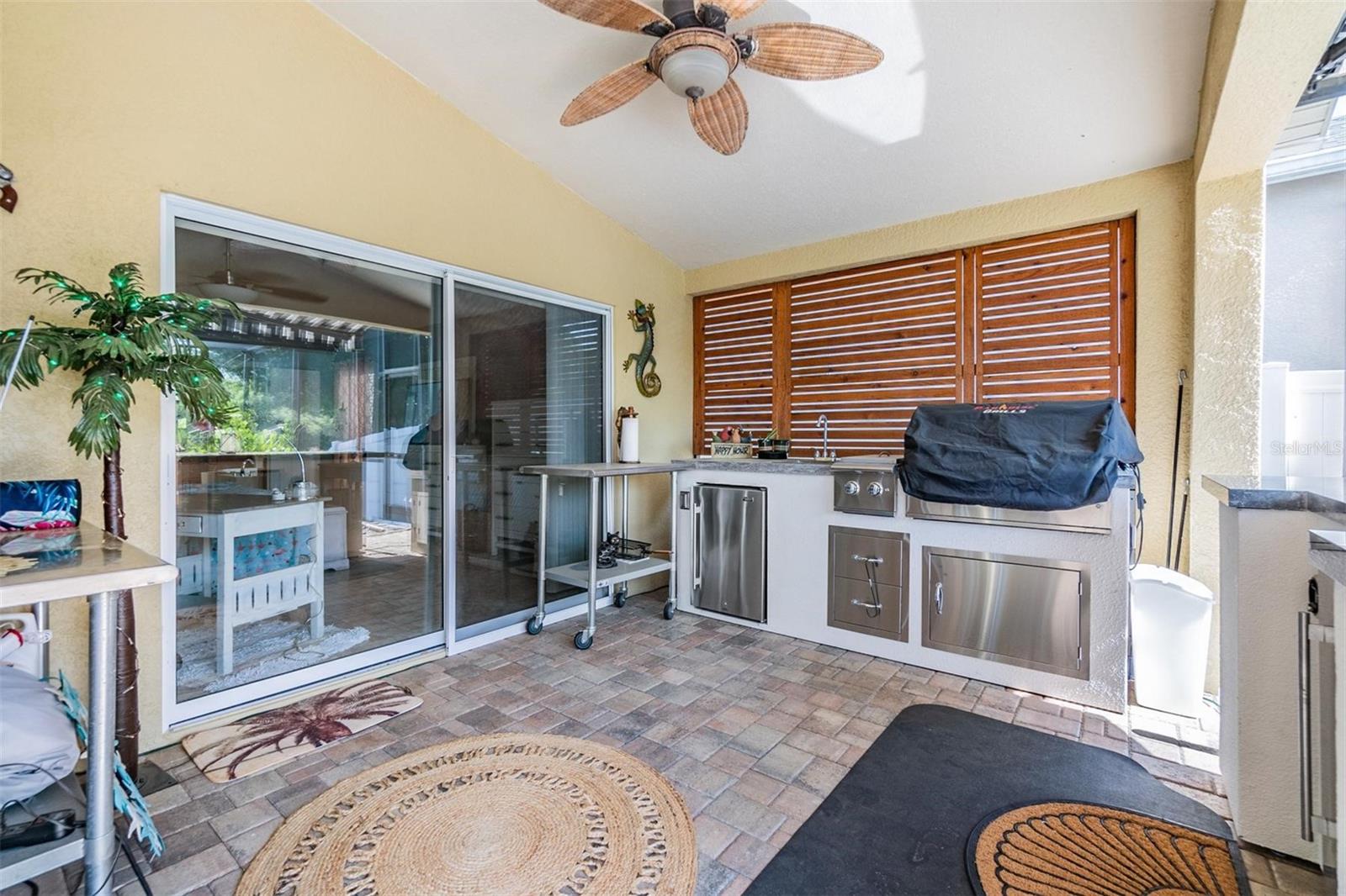 Outdoor covered kitchen, pavered lanai, ceiling fan and Electronic Shade Cover.