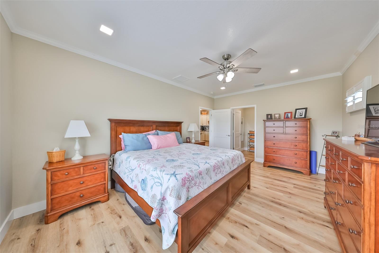 Primary bedroom is large enough for this king sized bed AND furniture WITH space to spare. Notice the attached ensuite primary bathroom with a large oversized walk in closet.