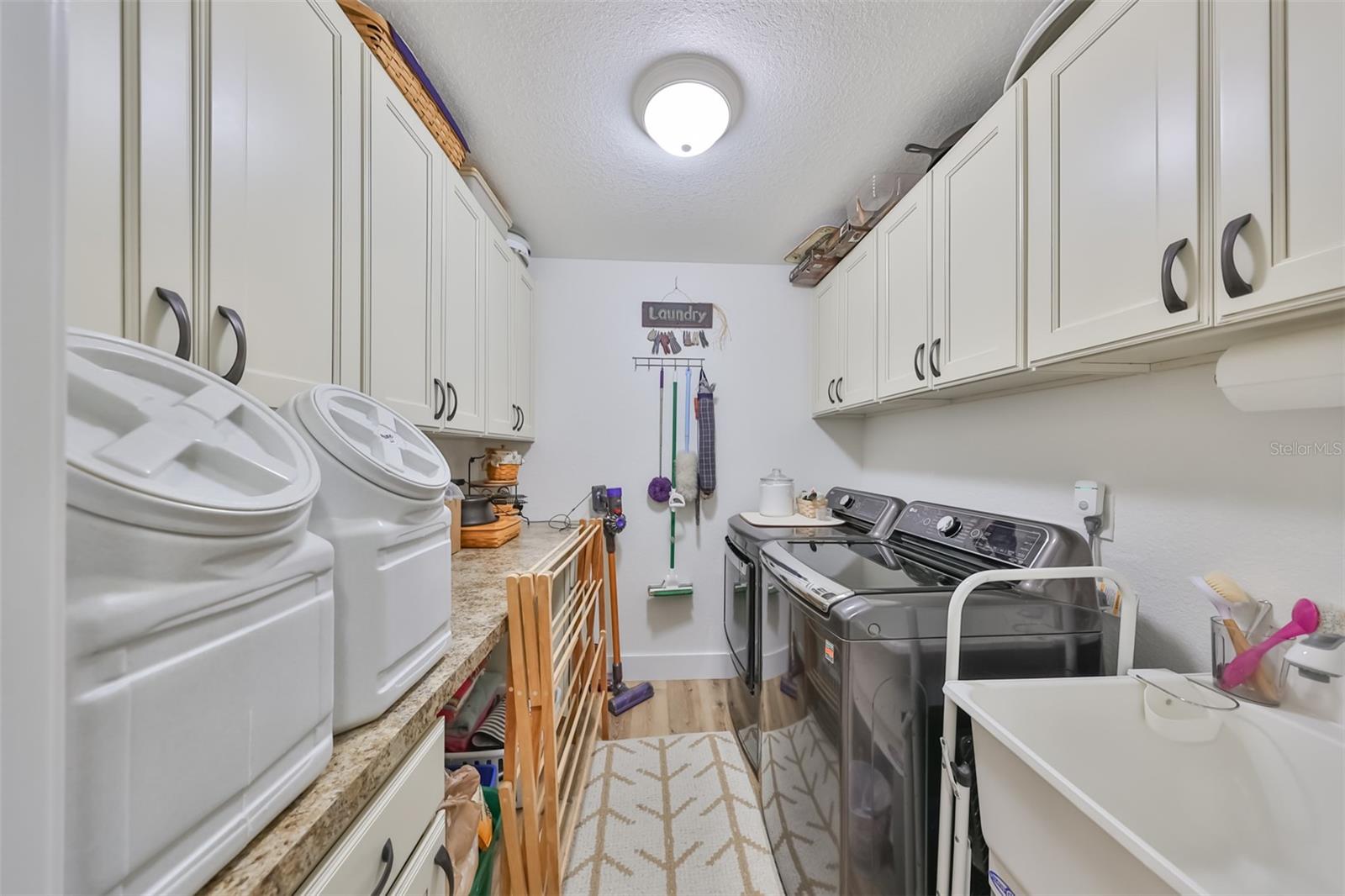 This large indoor laundry room has bright lights, TONS of cabinets for additional storage, utility sink and granite countertops to make doing laundry a breeze.