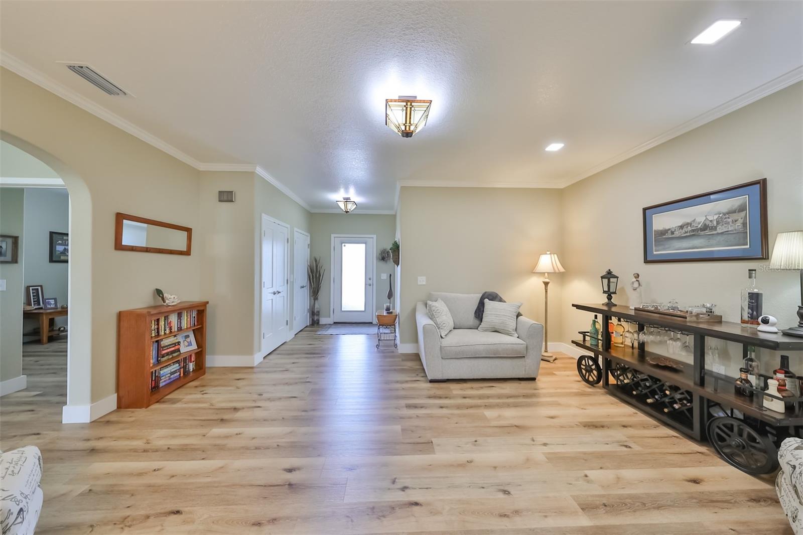 The front foyer/den has crown molding, large closets, natural colored laminate flooring and custom light fixtures.