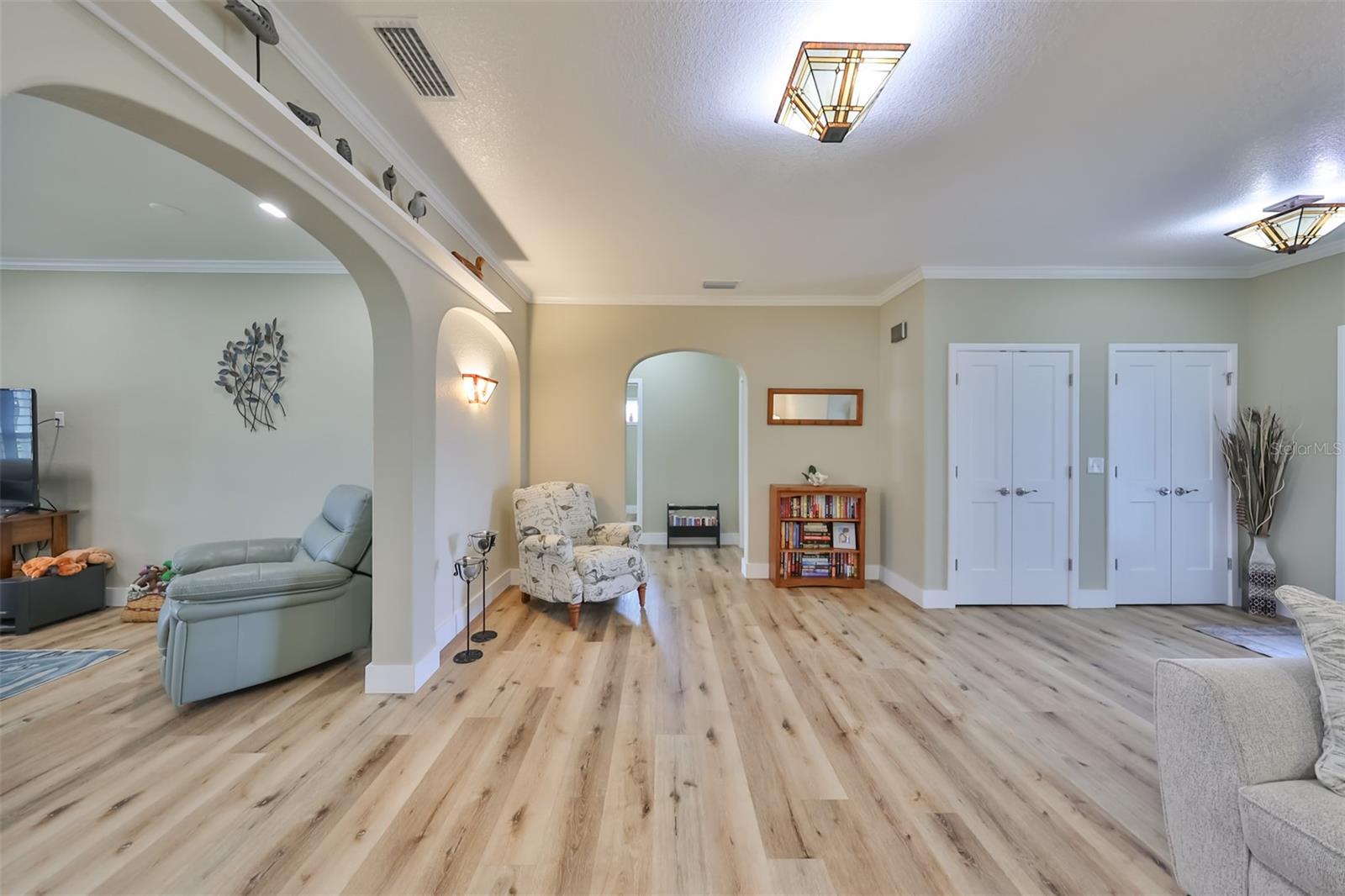 Arched doorways, crown molding, and custom lighting opens up from the entrance foyer/den into the living room. The small interior wall offers a little added privacy to separate the two rooms, while still creating an "open floor plan" feeling at the same time.