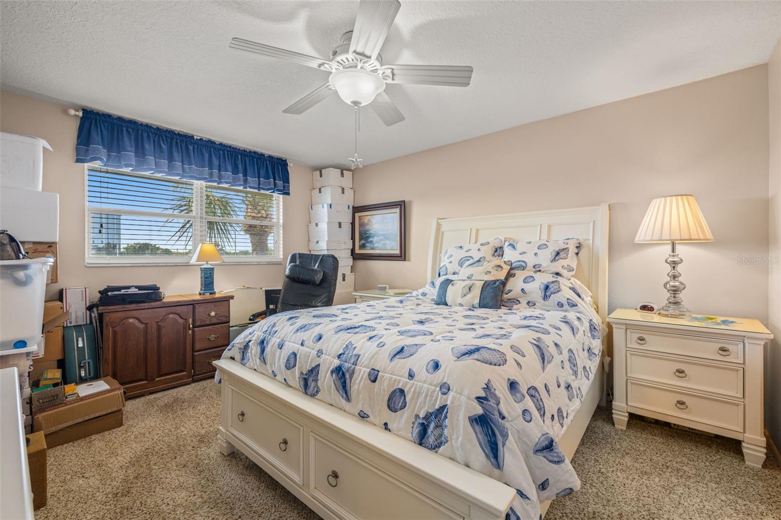 Primary bedroom which can easily accommodate a king-sized bed, features newer windows, ceiling fan, sliding glass door to the lanai, walk-in closet, extra storage/dresser space as well as attic access.