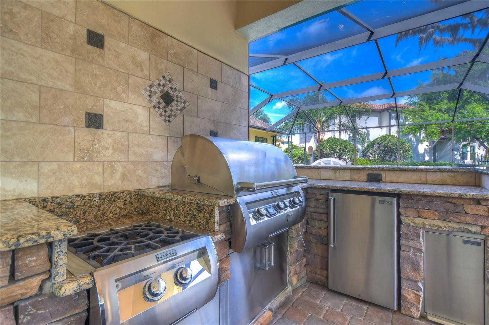 Top-of-the-line outdoor kitchen complete with a fire magic gas grill, burner, and fridge!