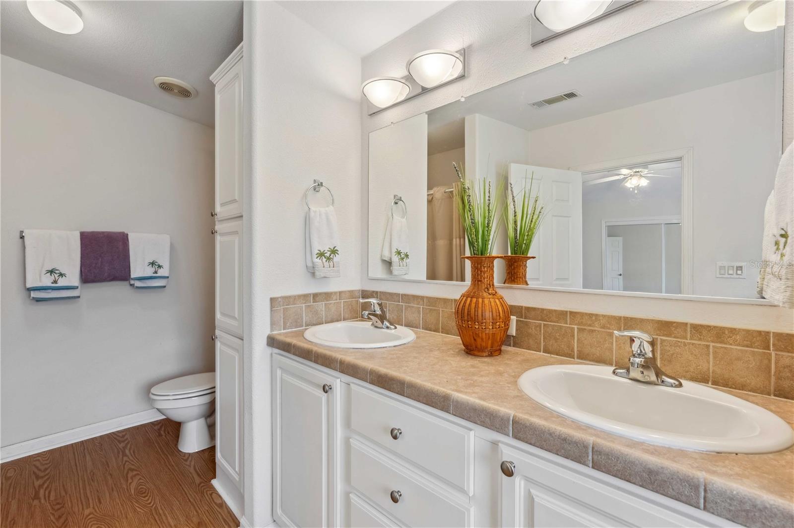 Primary retreat has double vanity, step-in shower, laminate flooring, and extra stoarge.