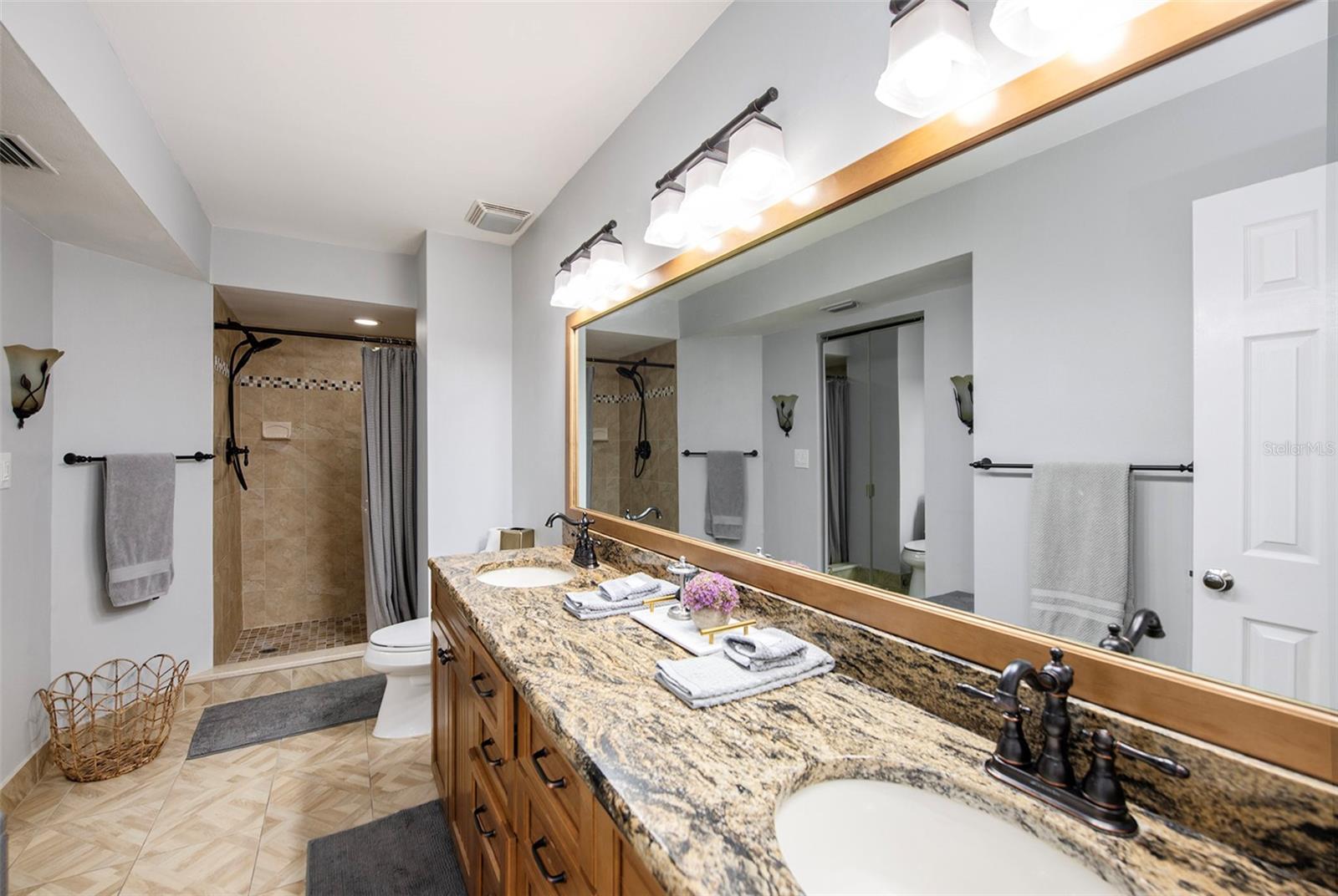 Master bathroom with beautiful finishes, dual vanity sinks, a walk in closet, and a shower