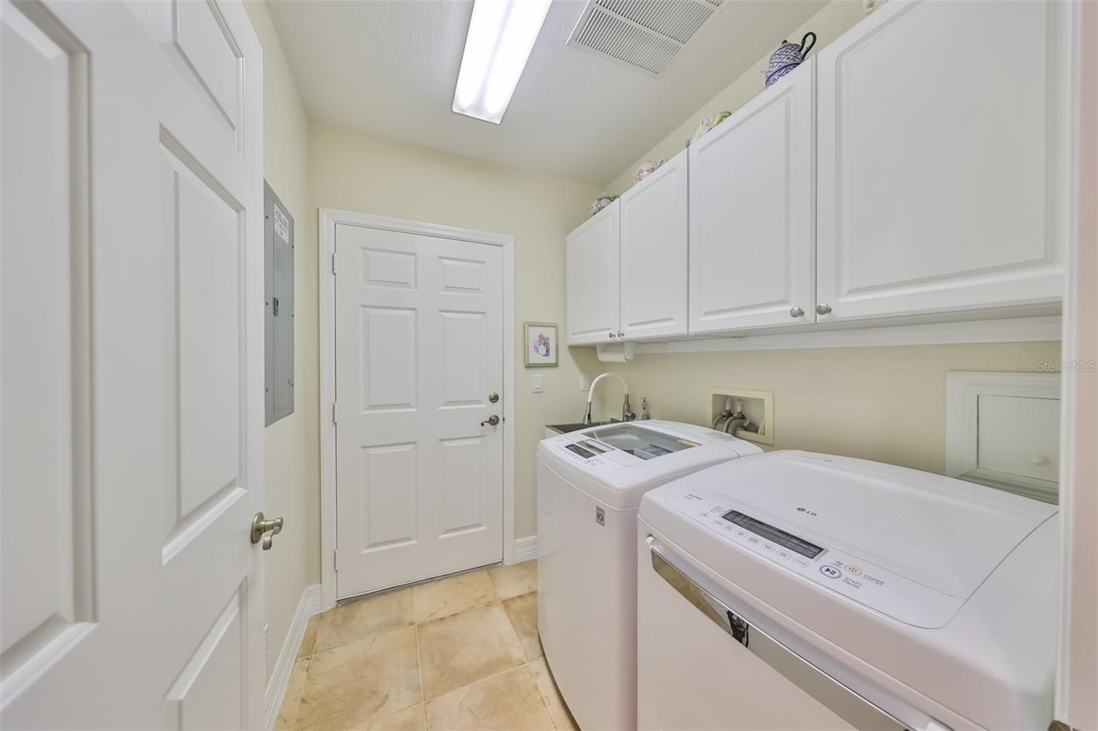 Separate indoor laundry room with washer and dryer and cabinets for storage. There is also a utility sink for added convenience.