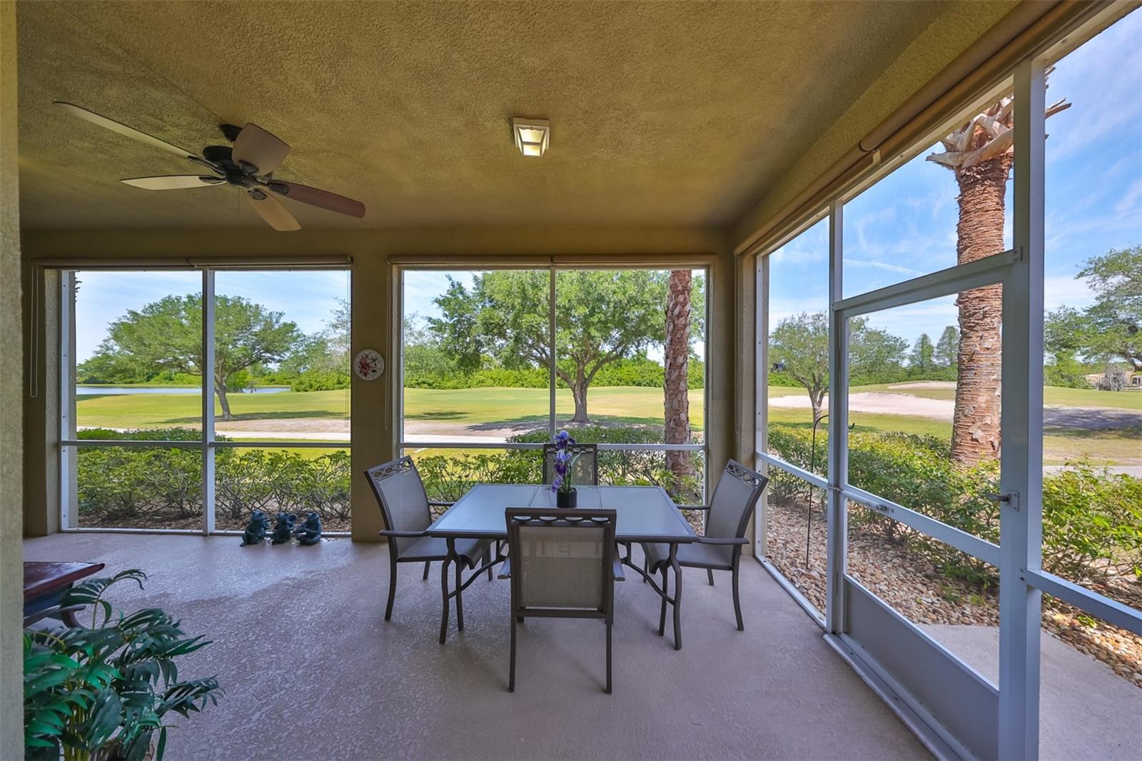 Screened patio with beautiful golf course view, a pond in the distance and a tropical ceiling fan for ultimate comfort.
