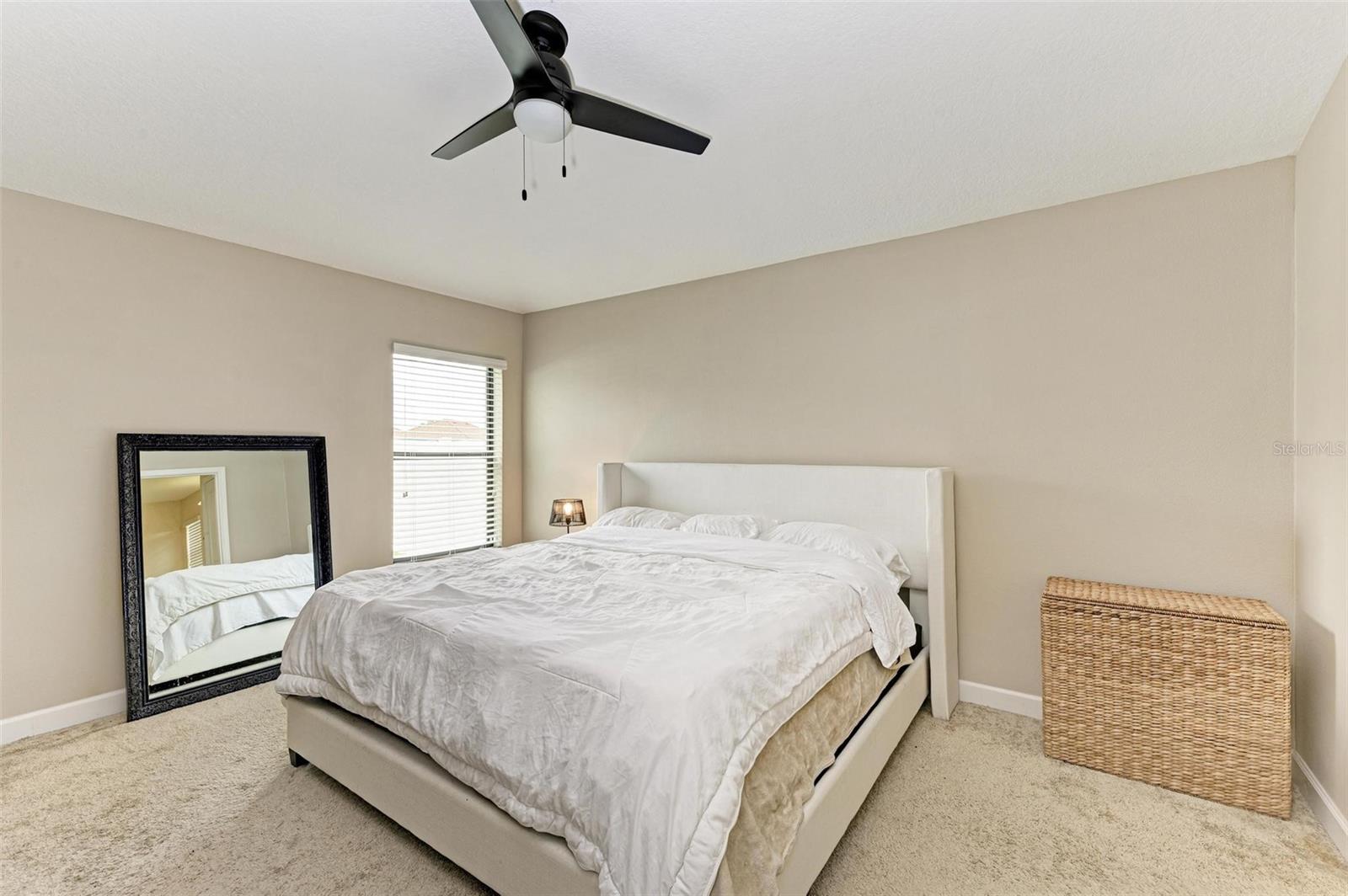 Primary bedroom has neutral paint and modern light fixtures..Beautiful natural light