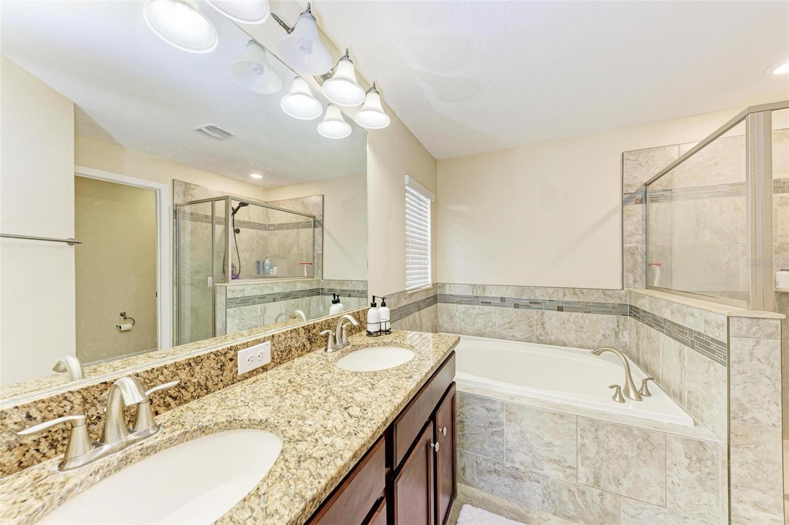 Primary bath with high end fixtures, granite, walk-in shower and soaking tub.  Look at those finishes!