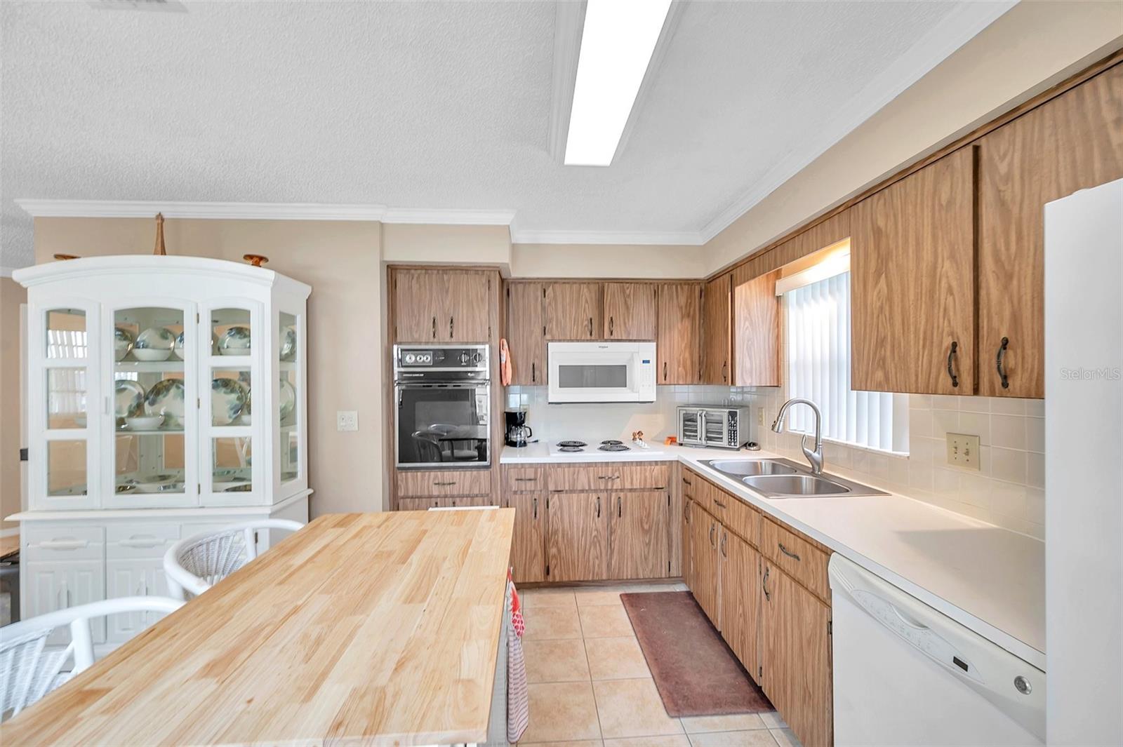 Kitchen view. Double stainless-steel sink with garbage disposal. It also included the refrigerator, built in microwave over the stovetop, built in wall oven, and dishwasher,