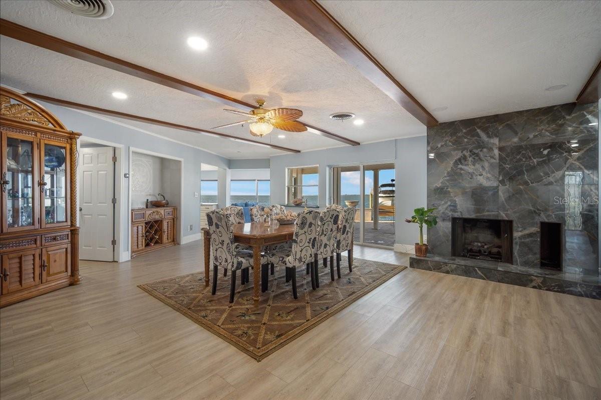 The open dining area seamlessly transitions with a marble fireplace and breathtaking water views.