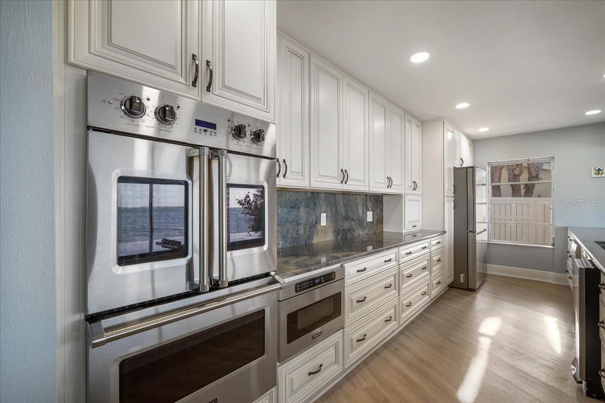 A authentic gourmet kitchen featuring a Viking French door double oven, built in cabinet microwave, elegant granite countertops, and ample counter space.