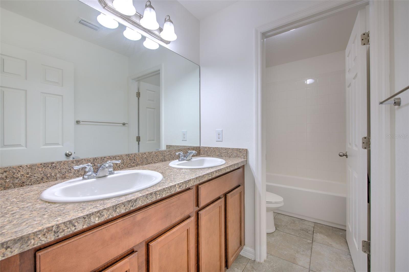 4th bathroom located between the secondary bedrooms upstairs. Dual vanity, shower/tub combo.