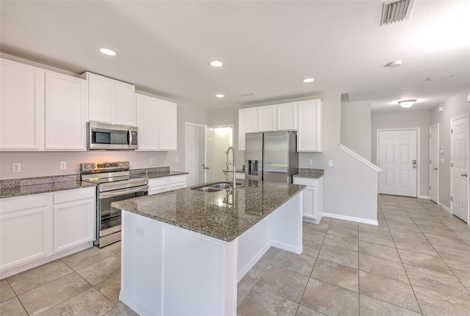 Kitchen with center island seating. Original kitchen appliances have been upgraded with stainless steel appliances. Granite counters with solid wood cabinetry.
