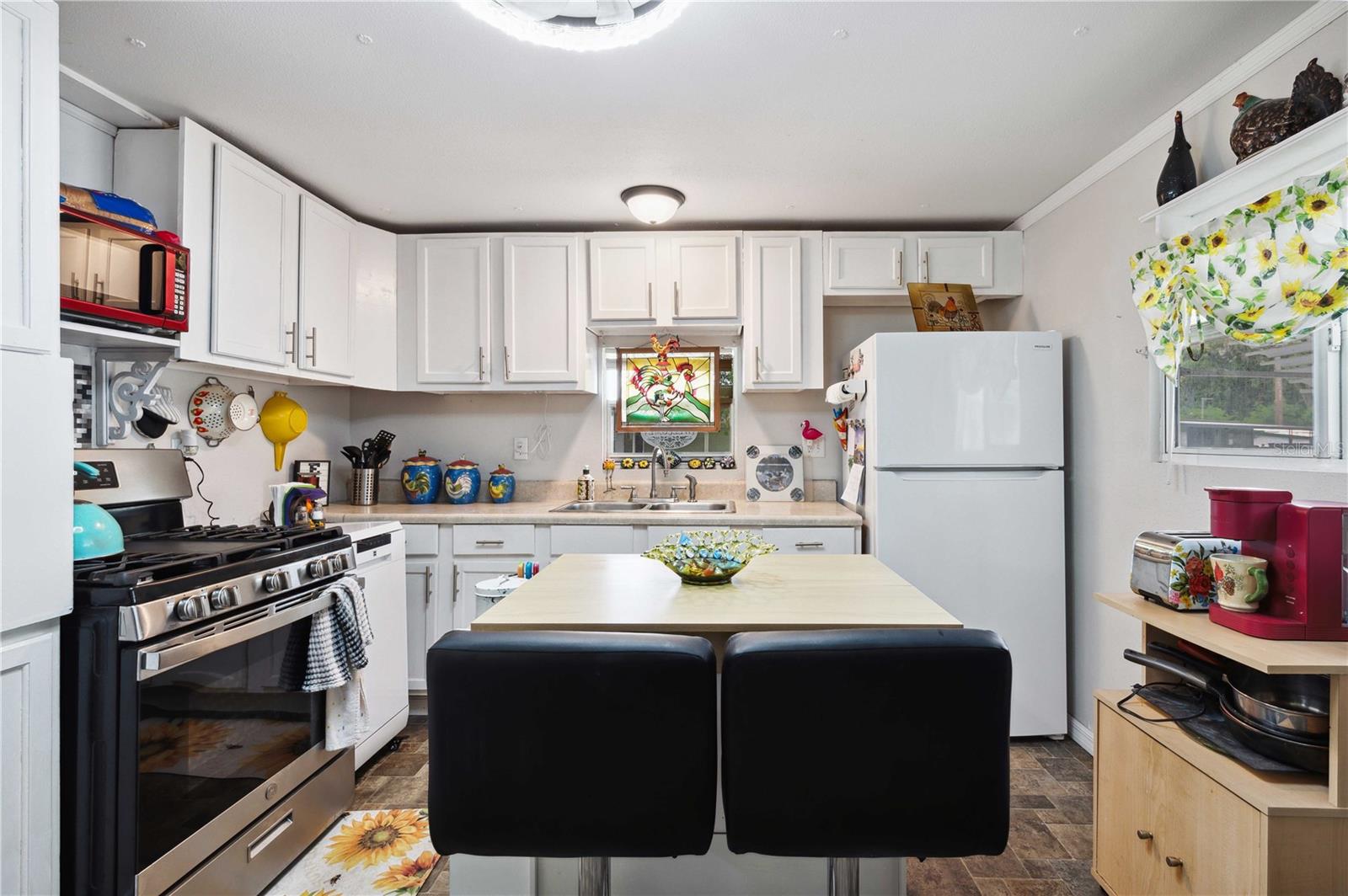 Kitchen has vinyl flooring, center island, updated appliances, and ample storage.