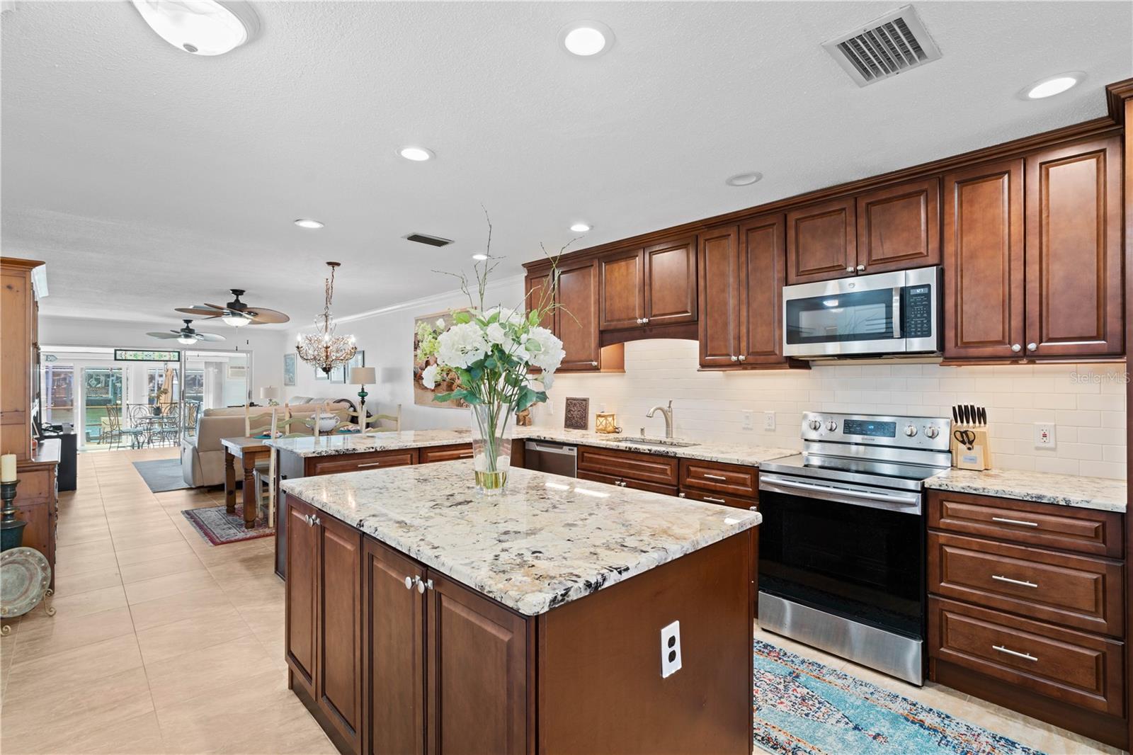 Spacious kitchen features Island with wood cabinetry and stone counters