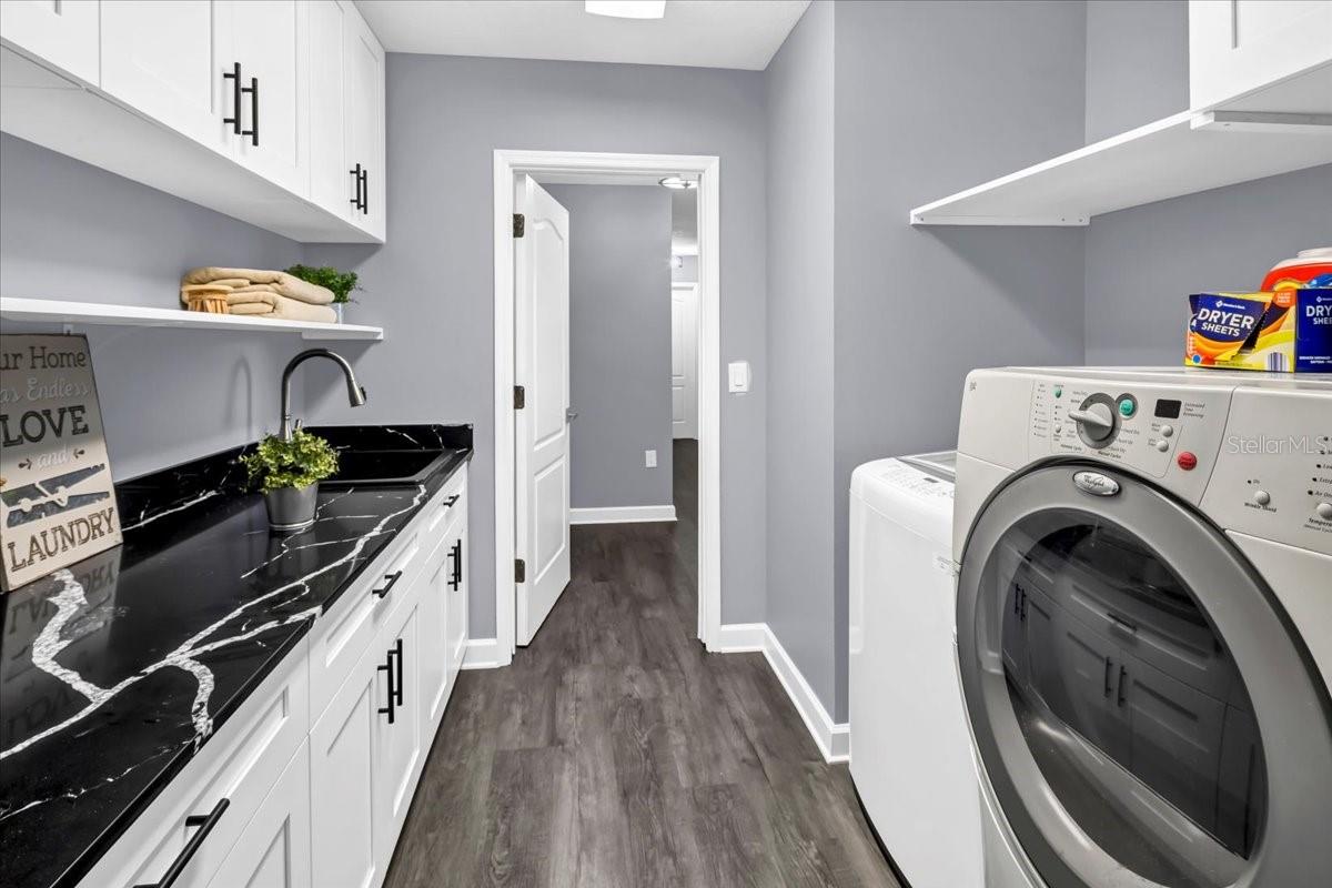 Laundry room with washer, dryer, utility sink and storage cabinets
