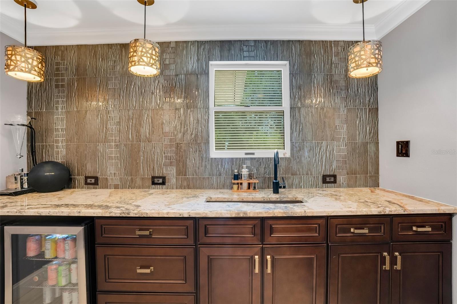 Wet bar (in office/flex space) with matching stone counterops and custom solid wood cabinets, sink and 2 wine/drink refrigerators