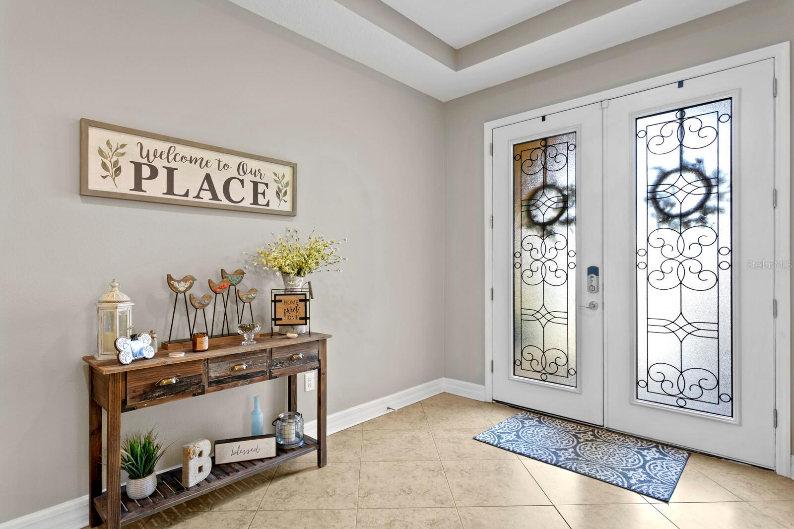 Your entryway features large tile flooring laid on a bias & tray ceilings.