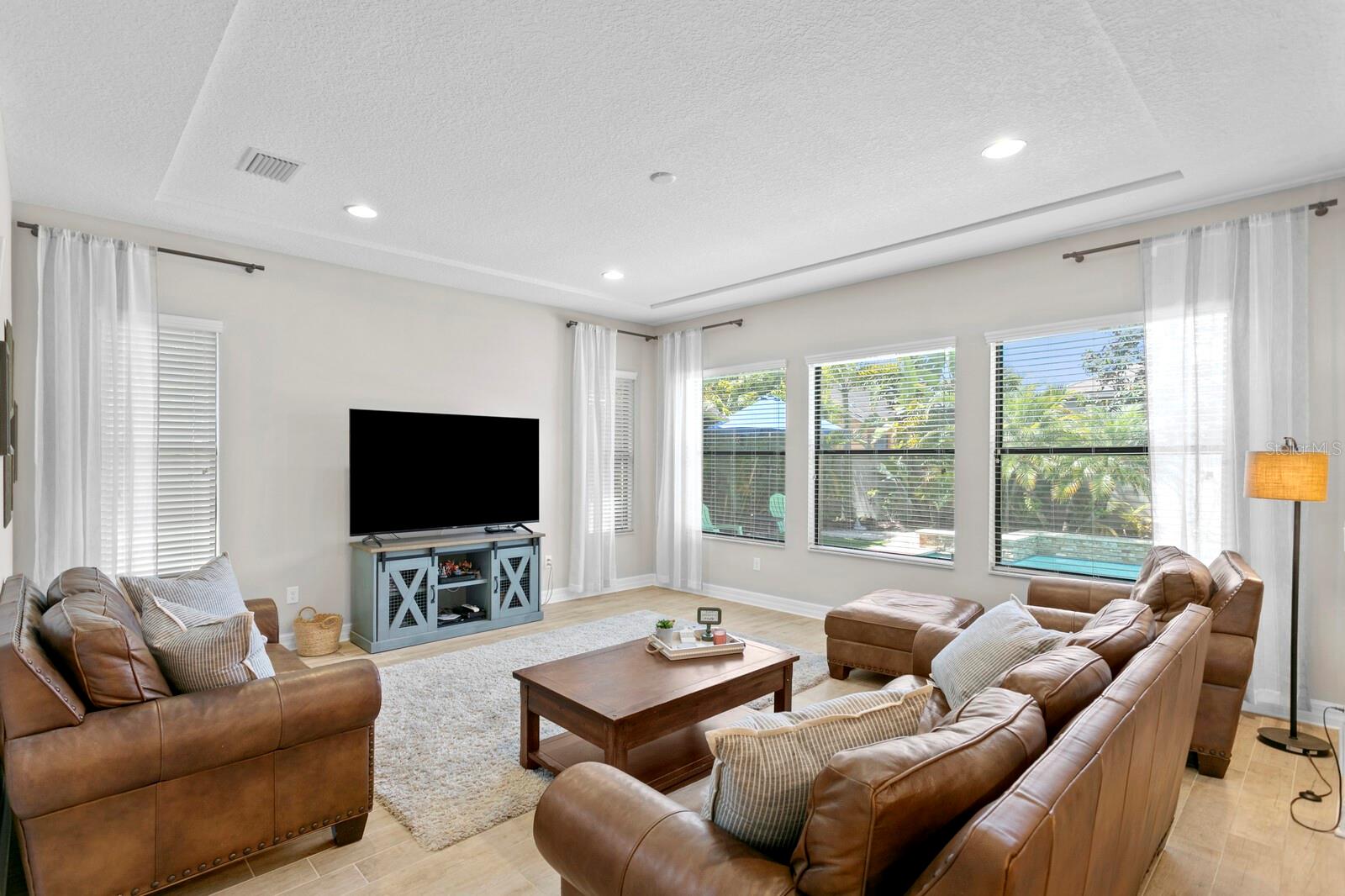 The living room has full outdoor views with lush mature landscaping.