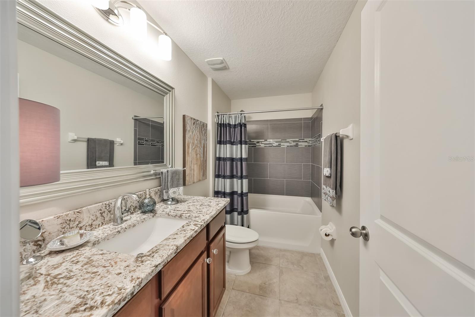 Guest bathroom is large, contemporary with upgraded tile work and granite counters.