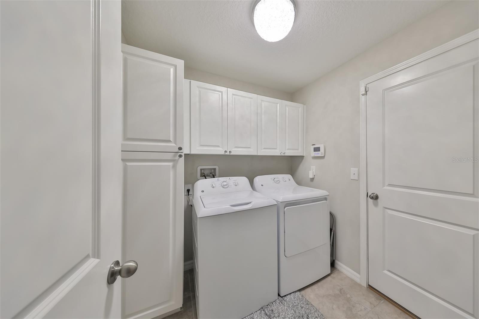 Laundry room has been upgraded with beautiful white cabinetry.