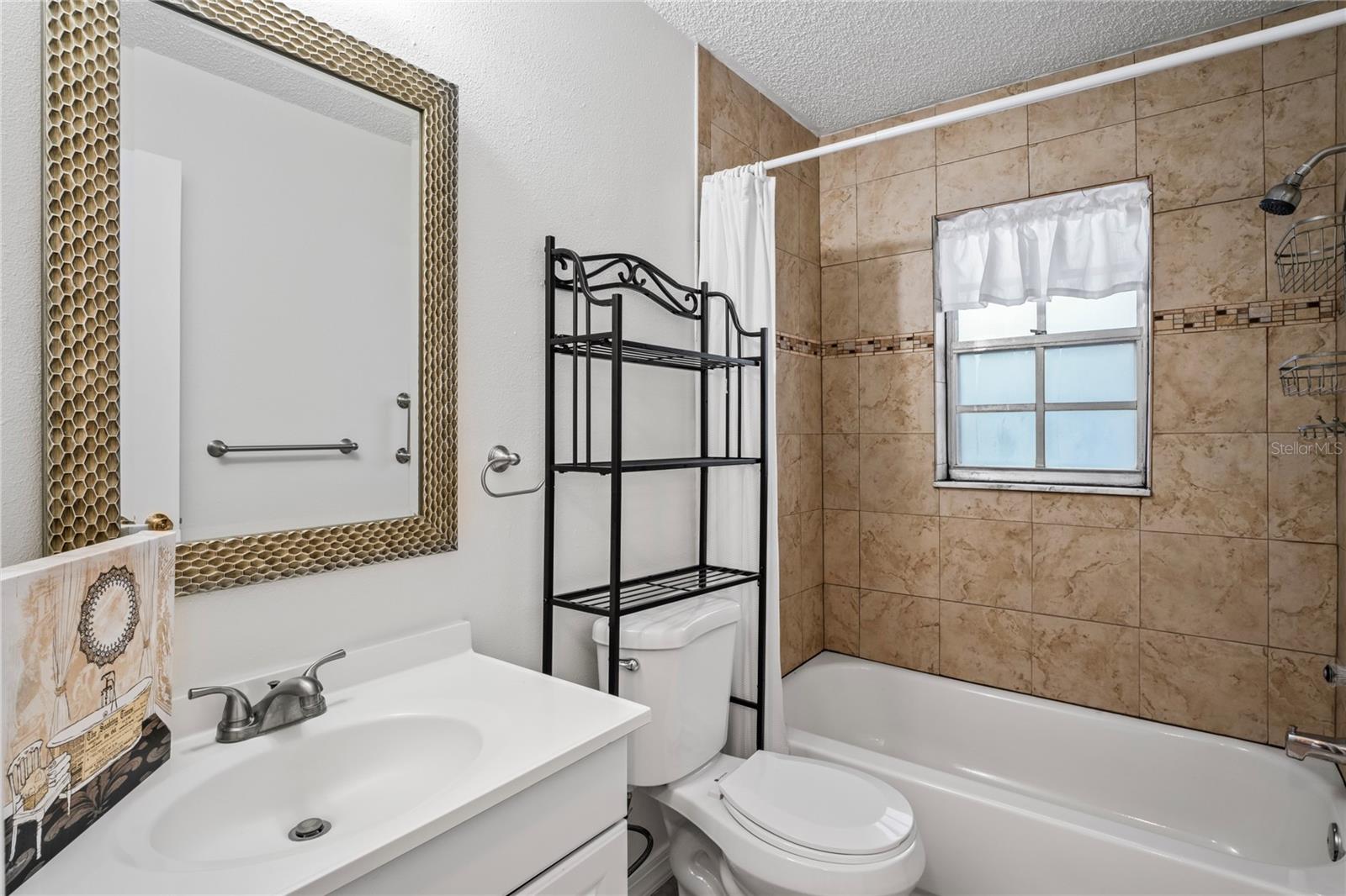 Guest bedroom offers a bathtub and shower, single vanity and a commode. The window is nice for ventilation and light.